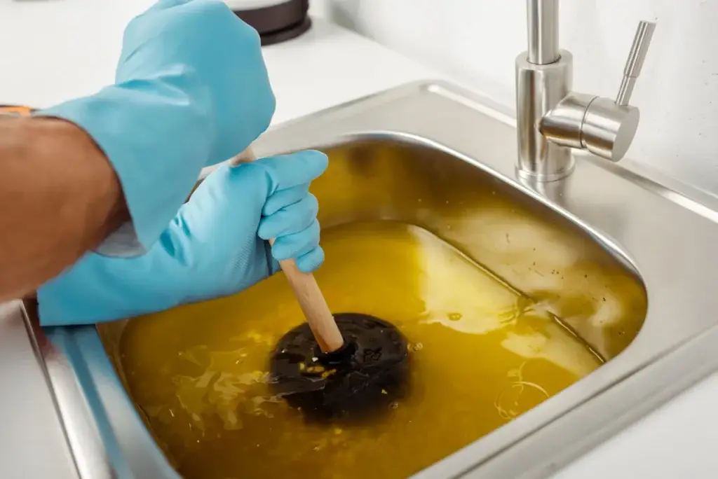 plumber using plunger to clear clogged sink
